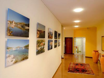 Gang met tapijt, stoelen en fotografische afbeeldingen aan de muur.