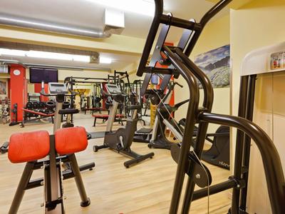 Binnenaanzicht van een sportschool met verschillende fitnessapparaten en houten vloer.