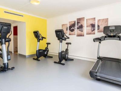 Palestra moderna con tapis roulant, cyclette e parete gialla.