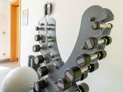 Vari manubri e una palla da ginnastica in una stanza per allenamento luminosa.