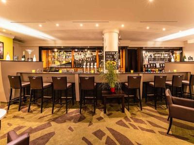 Bar dell'hotel moderna con sgabelli vuoti e illuminazione calda e accogliente.