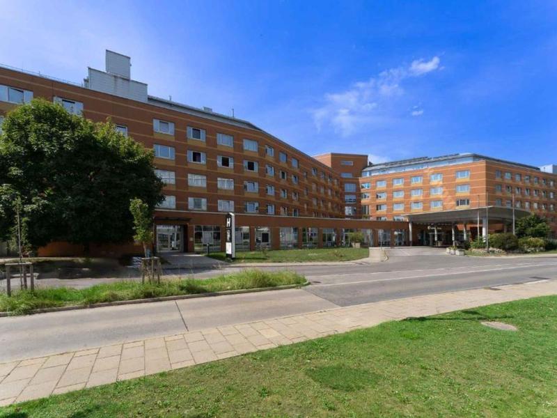 Groot hotelgebouw met meerdere verdiepingen en een ingang bij zonnig weer.