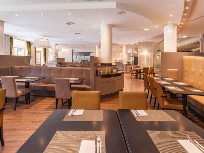 Licht restaurant met bruine en beige zitplaatsen, tafels en houten vloer.