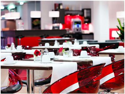 Moderní jídelna s bílými ubrusy a červenými židlemi v restauraci.