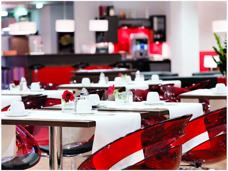 Moderní restaurace s červenými židlemi a bílými prostřenými stoly v hotelu.