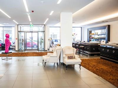 Heller Hotel-Eingangsbereich mit Sitzstühlen, braunem Teppich und großen Fenstern zur Straßenseite.