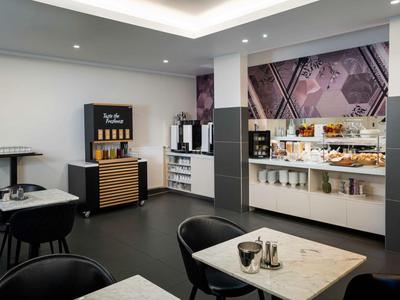 Modernes Frühstücksbuffet in stilvollem Hotel mit Sitzbereich und Kaffeeautomat.