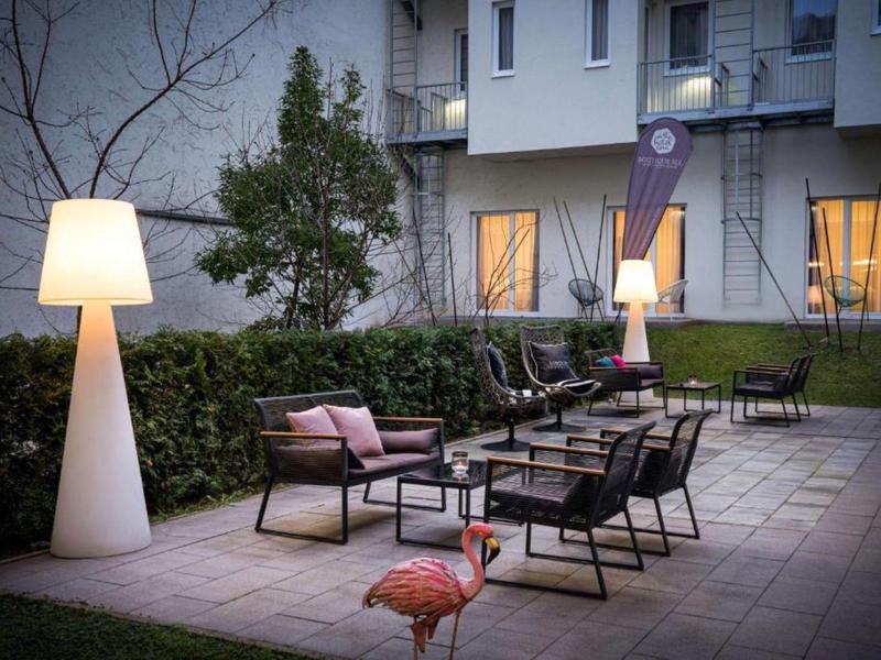 Salon extérieur confortable avec meubles modernes, éclairage et vue sur un bâtiment hôtelier.