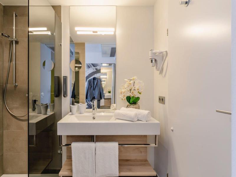 Moderní koupelna s umyvadlem, zrcadlem a bezbariérovým sprchovým koutem v neutrálních tónech