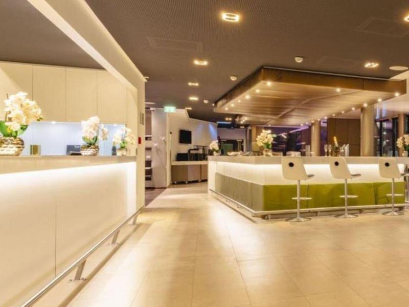 Světlá, moderní hotelová recepce s osvětlenou přepážkou a posezením.