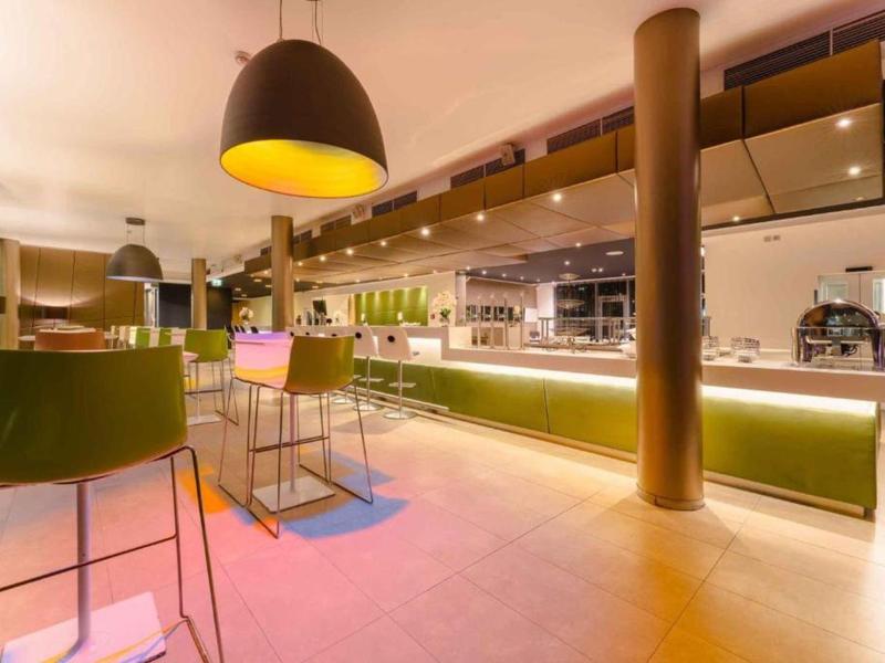 Moderně zařízený hotelový bar s vysokými stoličkami a teplým osvětlením.