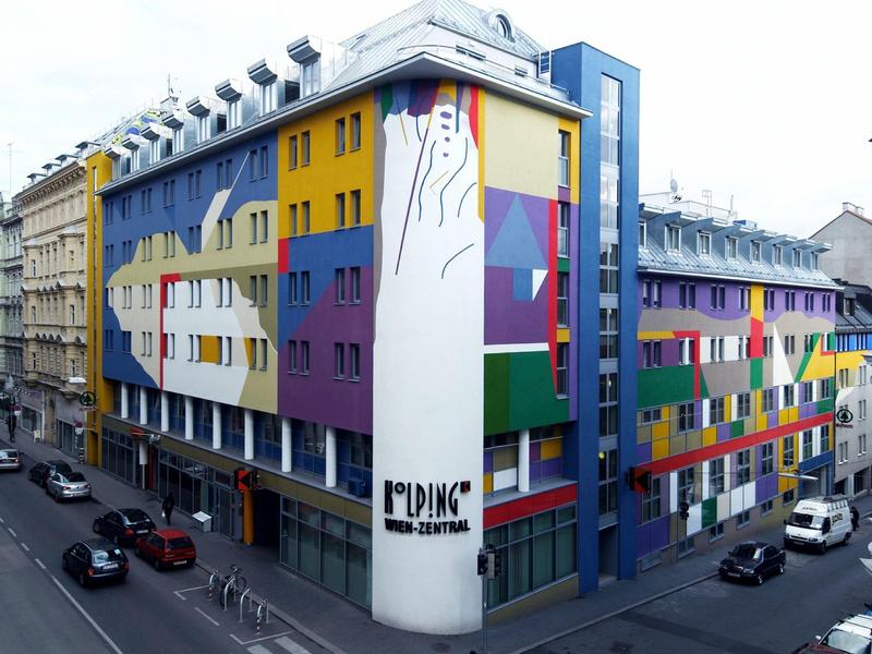 Kleurrijk beschilderd stadshotel met moderne architectuur op een straathoek.