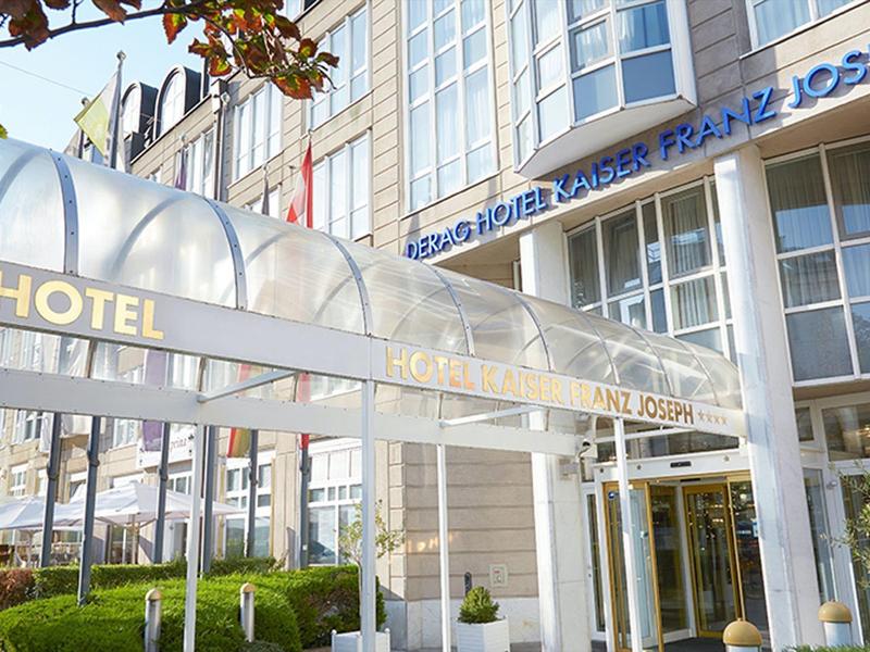 Vstup do moderního hotelu se skleněným přístřeškem a velkými okny.