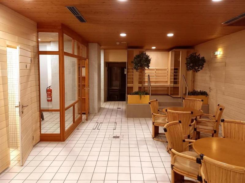 Vnitřní posezení se dřevěnými stoly a židlemi v chodbě s dlažbou na podlaze a stěnách.