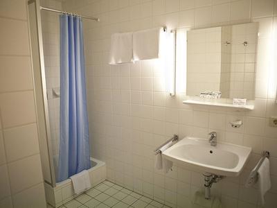 Pequeño baño con lavabo, espejo, toallas y cortina de ducha azul.