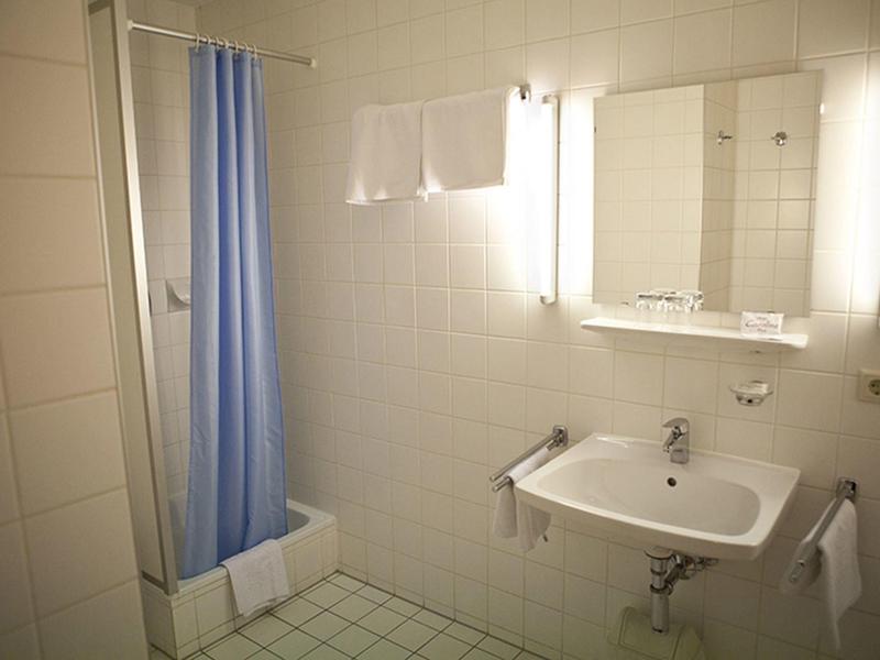 Malá koupelna s umyvadlem, zrcadlem a modrým sprchovým závěsem v neutrálních barvách