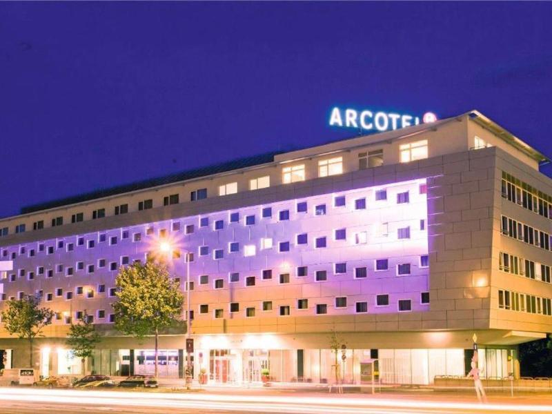 Edificio de hotel moderno con muchas ventanas, iluminado de noche bajo un cielo oscuro.