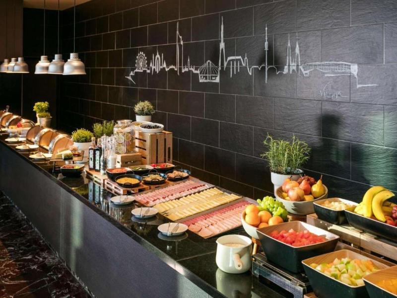 Buffet de desayuno con frutas, pan y platos variados en un entorno moderno y elegante.