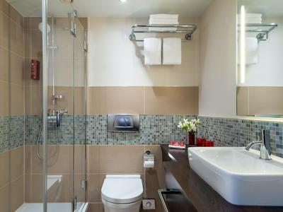 Modern bathroom with glass shower, toilet, and white sink on dark vanity