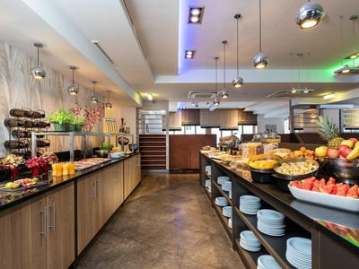 Modern hotelontbijtbuffet met vers fruit en gebak in een lichte ruimte.