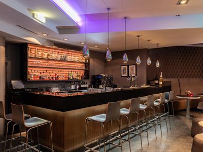 Moderne hotelbar met verlichte bar, barkrukken en gezellige zitgedeeltes.