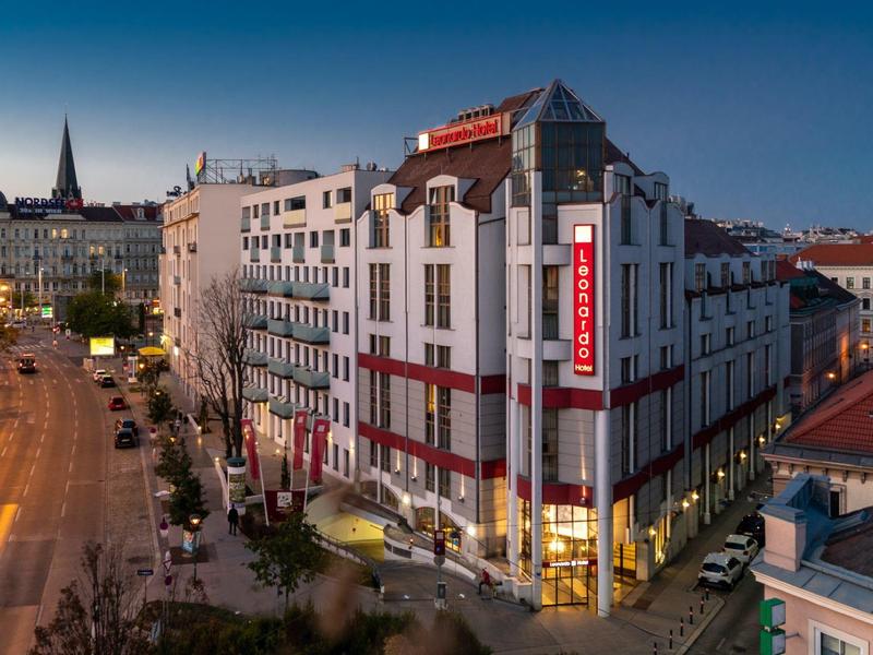 Stedelijk hotelgebouw met verlicht bord in de schemering