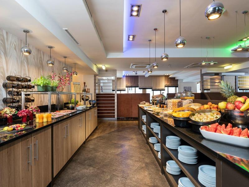 Modern hotelontbijtbuffet met vers fruit en gebak in een lichte ruimte.