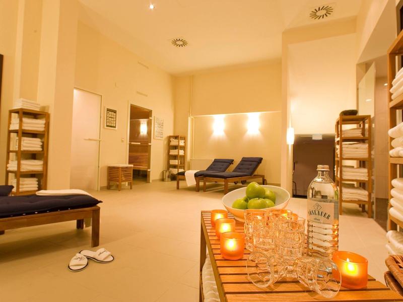 Salle de spa chaleureuse avec chaises longues, étagères à serviettes, bougies et éclairage d'ambiance.