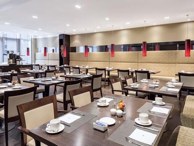 Moderní hotelová restaurace s prostřenými stoly, židlemi a stylovým osvětlením.