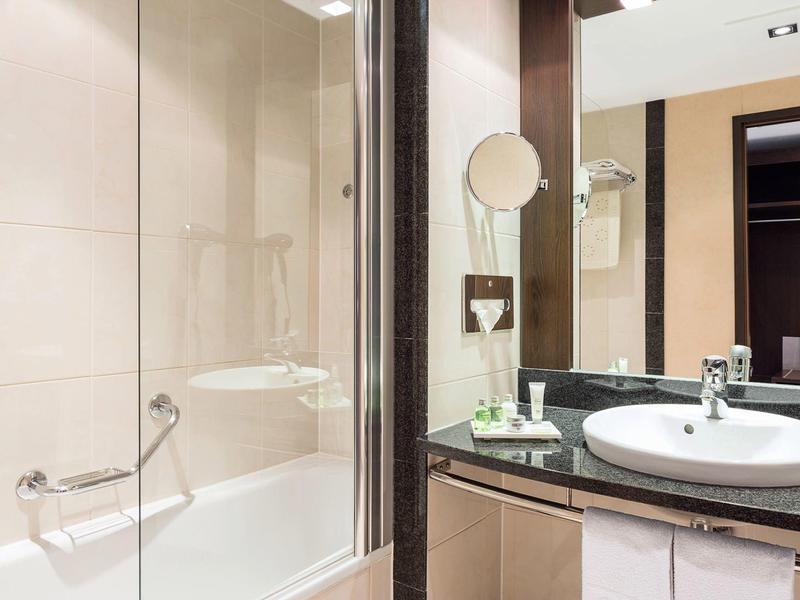 Nowoczesna łazienka z wanną, umywalką i dużym lustrem w hotelu.