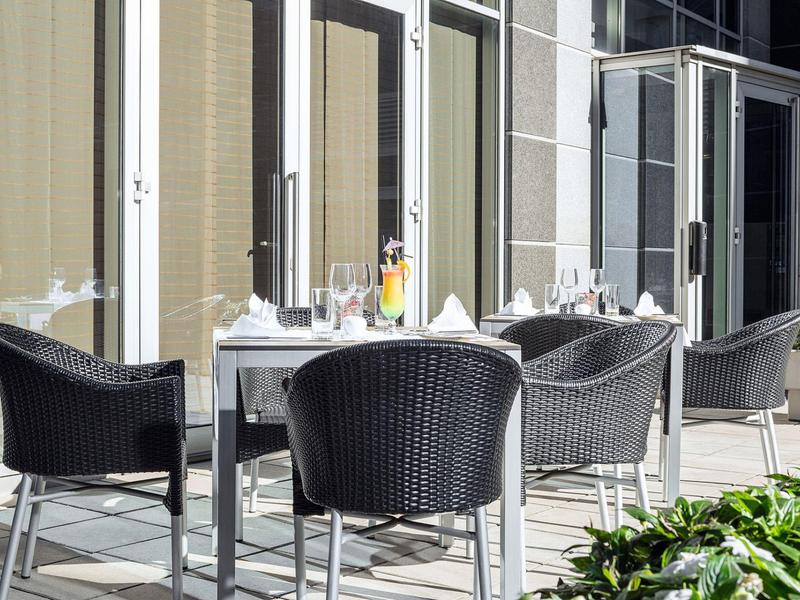 Nowoczesna zewnętrzna część hotelu z stołem i czarnymi wiklinowymi krzesłami na tarasie.