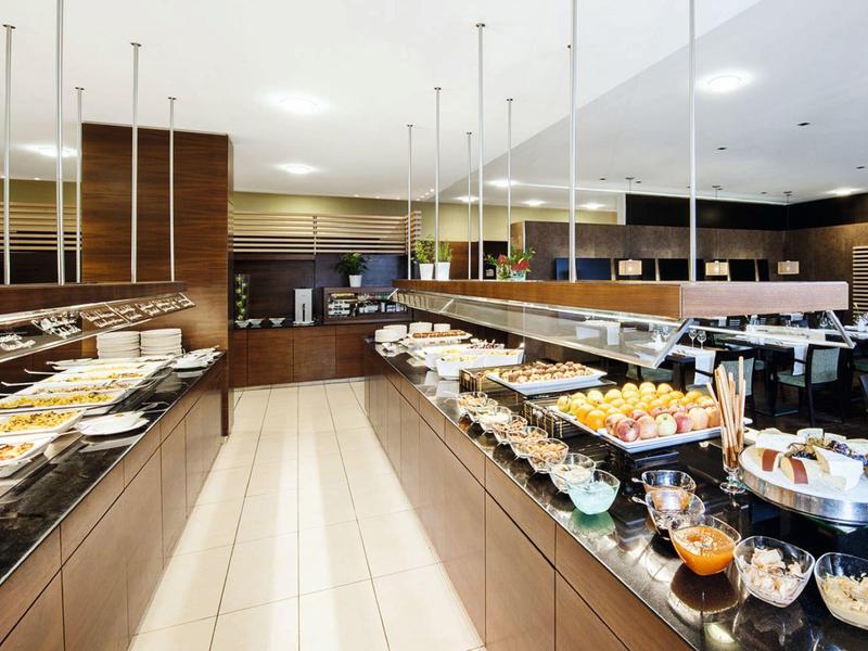 Hell beleuchteter Raum mit Buffet, zwei langen Theken voller Speisen und modernem Interieur.