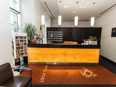 Modernes Empfangsbereich mit orange beleuchtetem Tresen, Sitzgelegenheiten und Pflanzen.