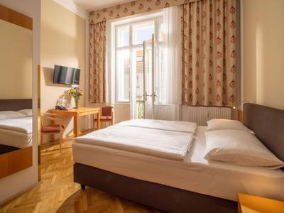 Lichte hotelkamer met tweepersoonsbed, bureau, stoel en groot raam met gordijnen