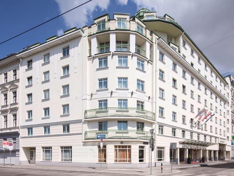 Velká bílá hotelová budova s několika patry a mnoha okny pod oblačnou oblohou.