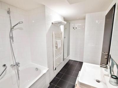Modern bathroom with bathtub, shower, sink, and towel heater in white and black