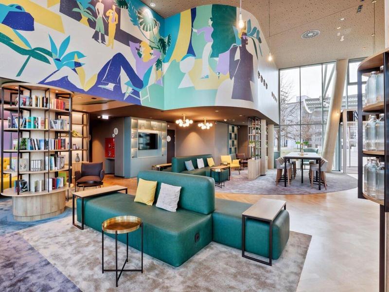 Modernly furnished hotel lounge area with seating groups and large windows.