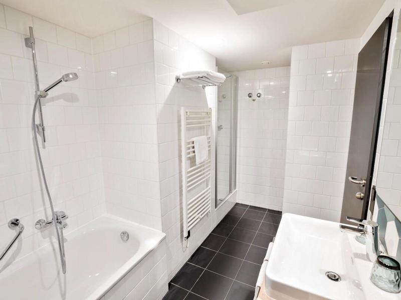 Modern bathroom with bathtub, shower, sink, and towel heater in white and black