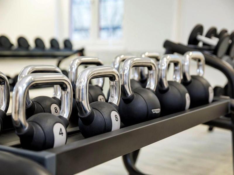 Row of black and silver kettlebells in a gym.