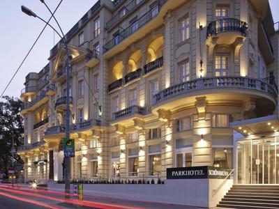 Verlicht klassiek hotelgebouw met balkon en elegante ingang bij schemering.