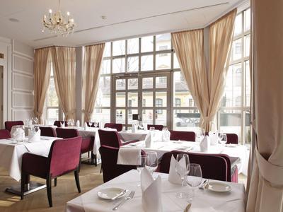 Elegant restaurant met gedekte tafels en grote ramen met lichte gordijnen.