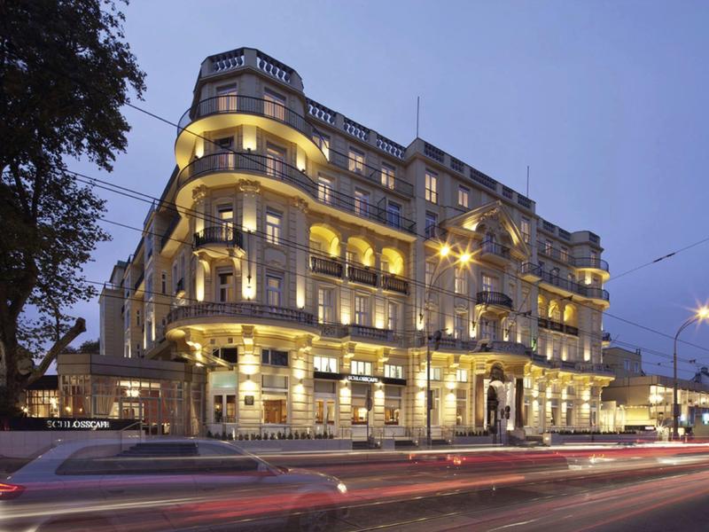 Osvětlená historická vícepatrová budova hotelu večer s stopami světel aut.