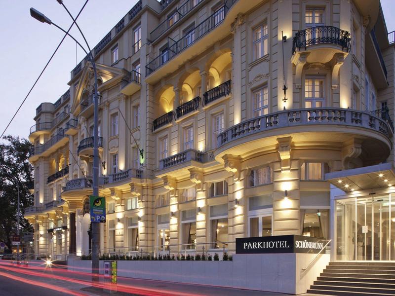 Večerní pohled na osvětlený historický hotel na městské ulici.