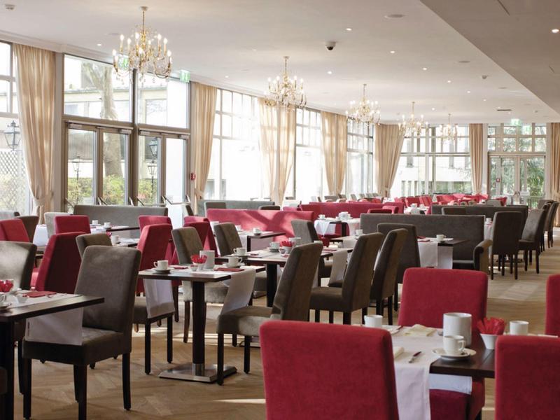 Světla, moderní restaurace s červeným a šedým nábytkem a velkými okny.