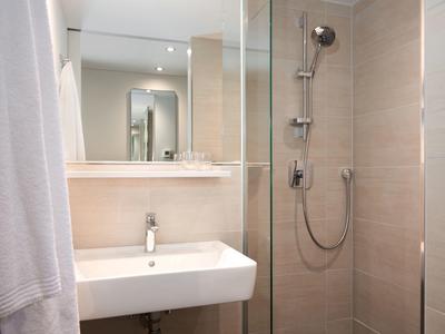 Small modern bathroom with sink, mirror, and glass shower.