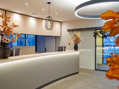 Moderne helle Empfangshalle mit geschwungenem Tresen, dekorativen Vasen und warmen Lichtakzenten.