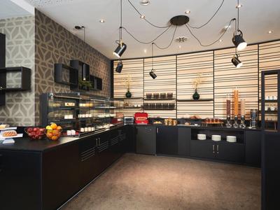 Modern hotel bar with dark furniture, fruit bowl, and illuminated shelf in the background.