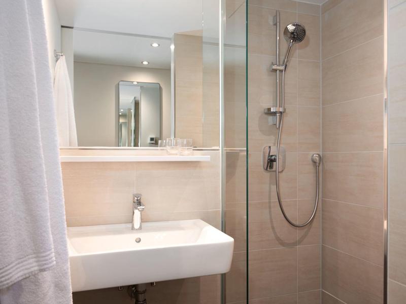 Small modern bathroom with sink, mirror, and glass shower.