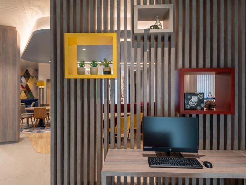 Angolo computer moderno con mensole colorate a parete e piante decorative.