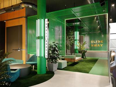 Modern hotel room with green color scheme, plants, and cozy seating areas.